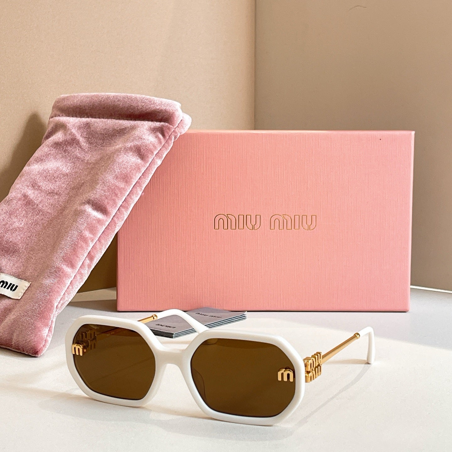 MiuMiu sunglasses with white oversized frames, dark lenses, and gold logo detailing