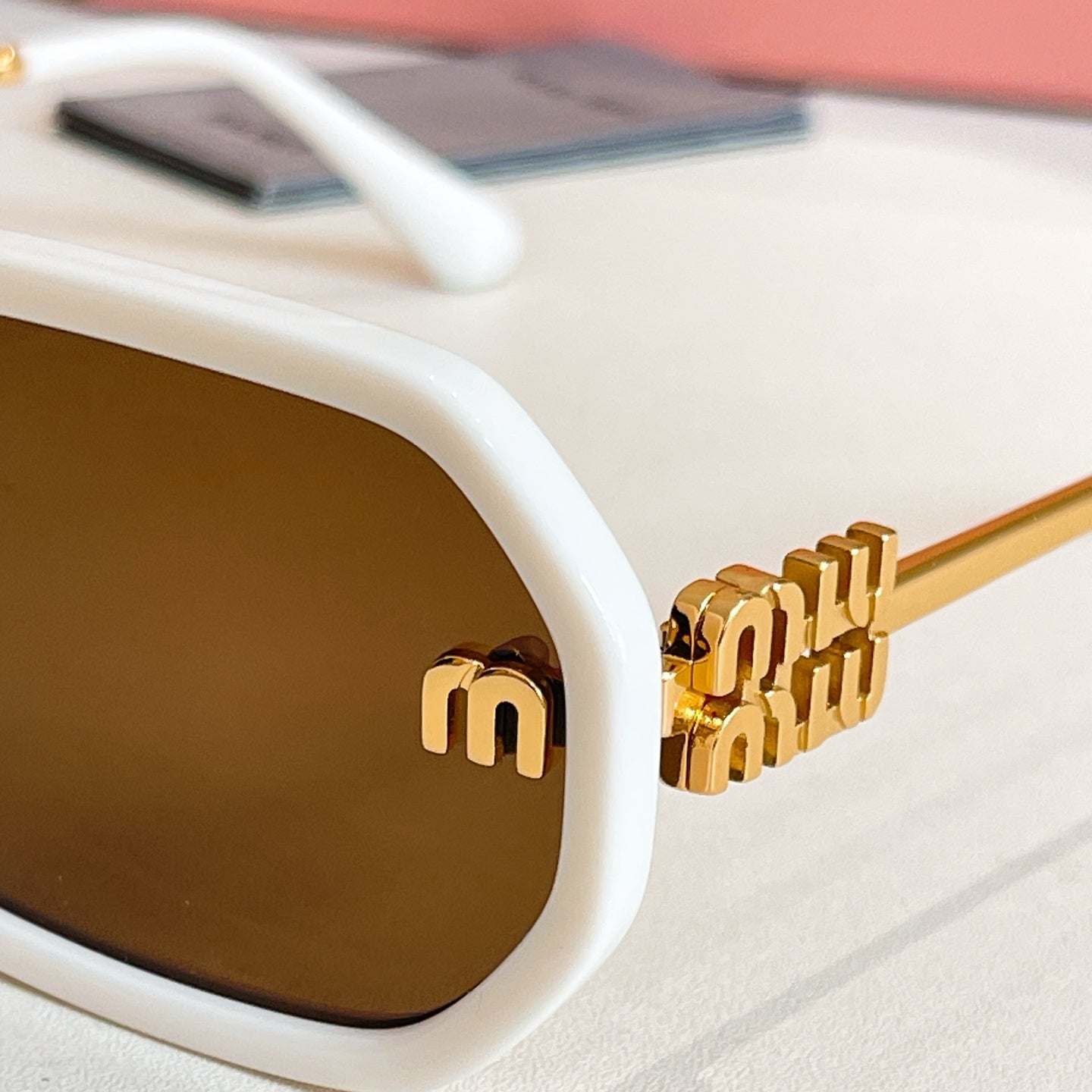 MiuMiu white sunglasses lens with gold logo on temple and dark tinted lens