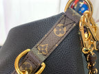 Louis Vuitton monogram strap detail with gold rings and orange tab on black leather
