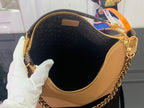 Louis Vuitton small bag with tan leather base, dark monogram lining, and gold zipper top.