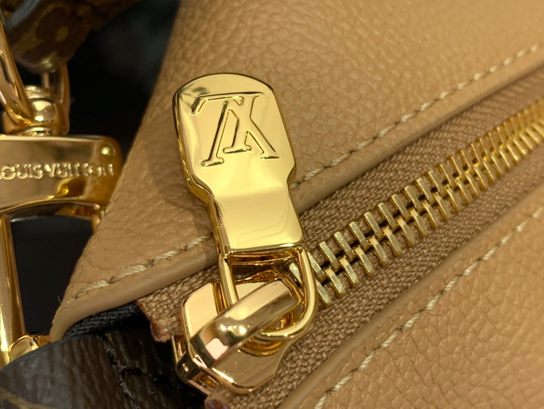 Louis Vuitton bag zipper pull and gold hardware on tan pebbled leather.