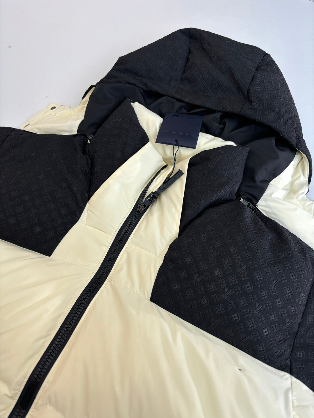 Black and cream hooded puffer jacket close-up with zipper and inner hood