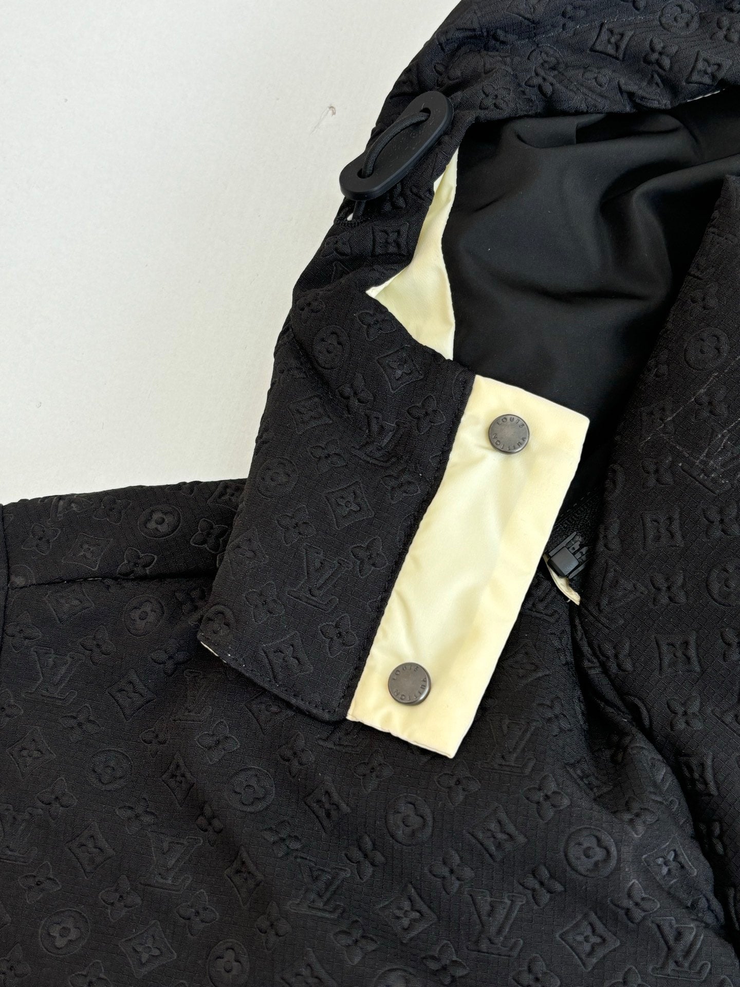Monogram-style puffer jacket hood and snap placket, black fabric with cream trim