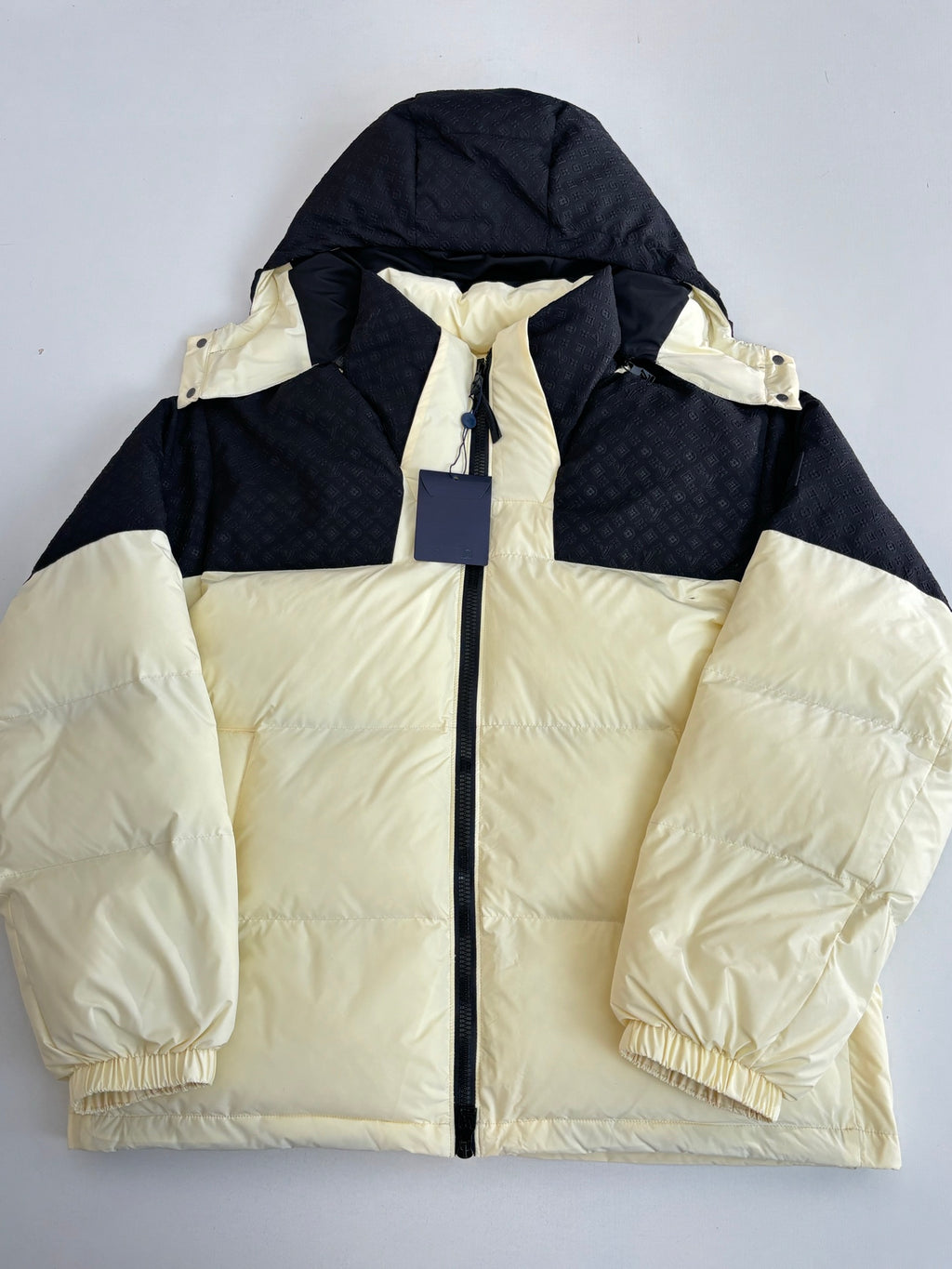 Two-tone hooded puffer jacket, cream body with black sleeves and drawstring hood
