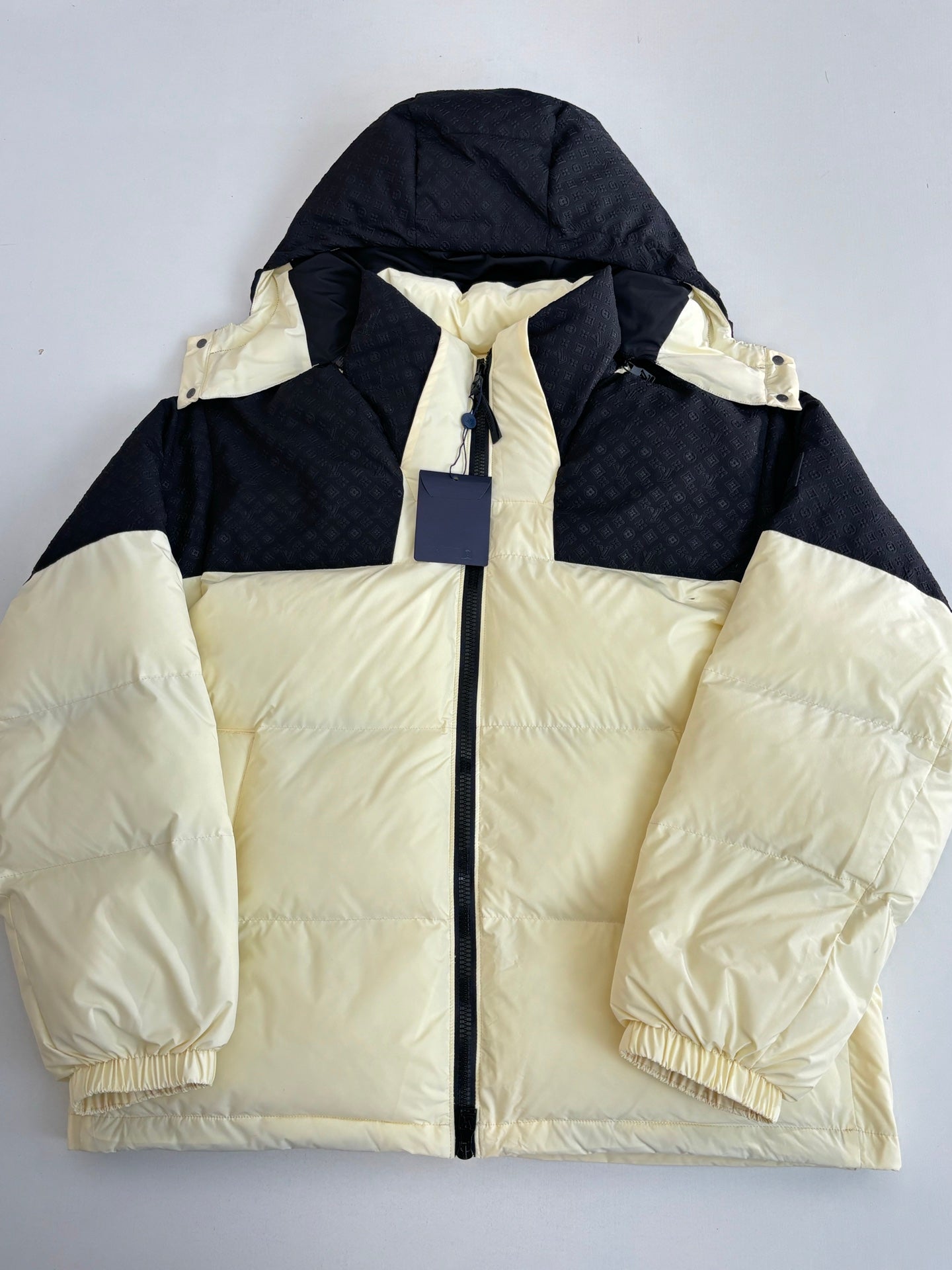 Two-tone hooded puffer jacket, cream body with black sleeves and drawstring hood