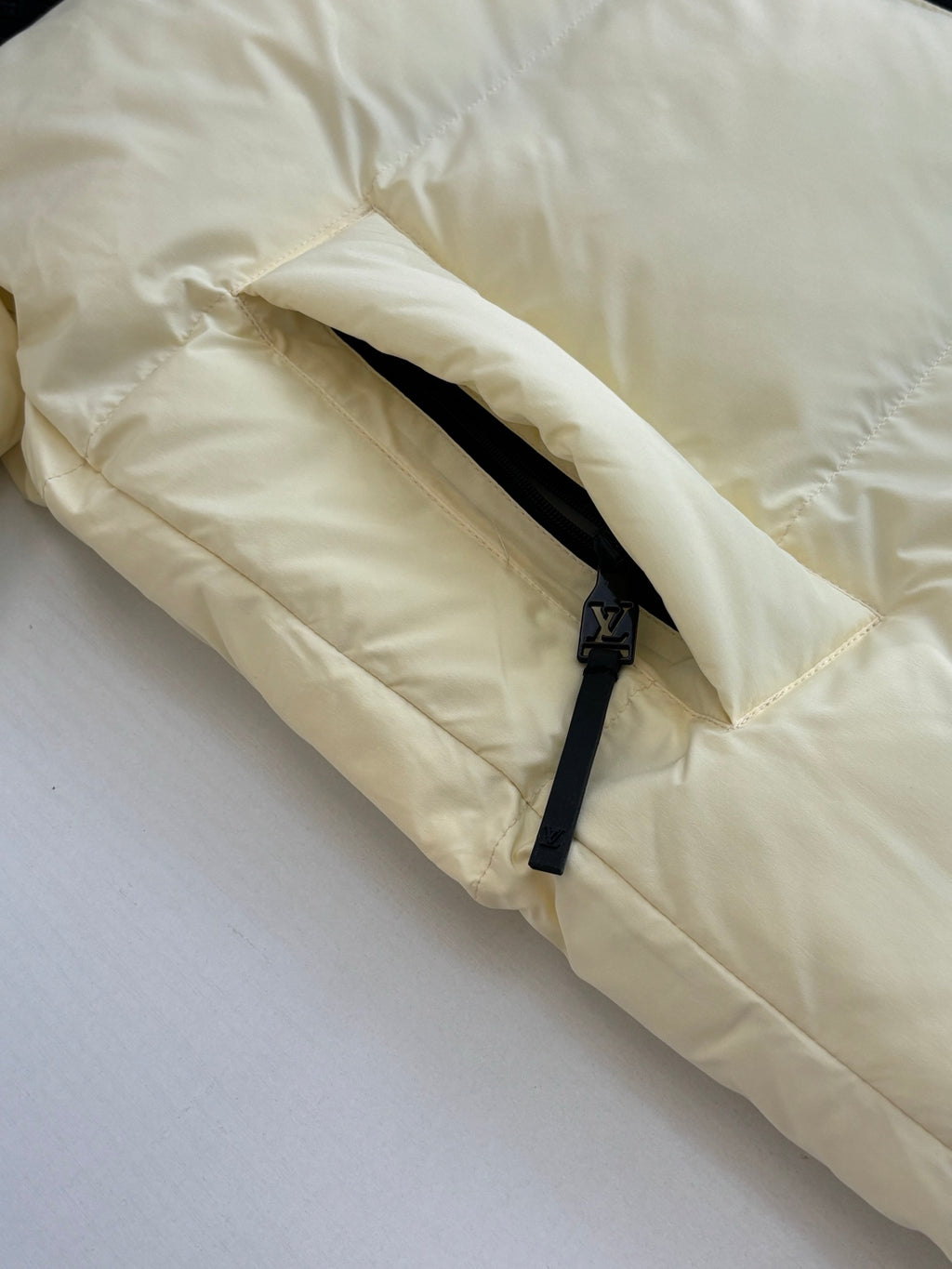 Cream puffer jacket sleeve close-up with black zipper detail and drawcord cuff
