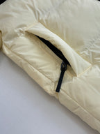 Cream puffer jacket sleeve close-up with black zipper detail and drawcord cuff