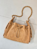 Tan quilted suede handbag with gold-tone chain strap and front eyelet hardware.