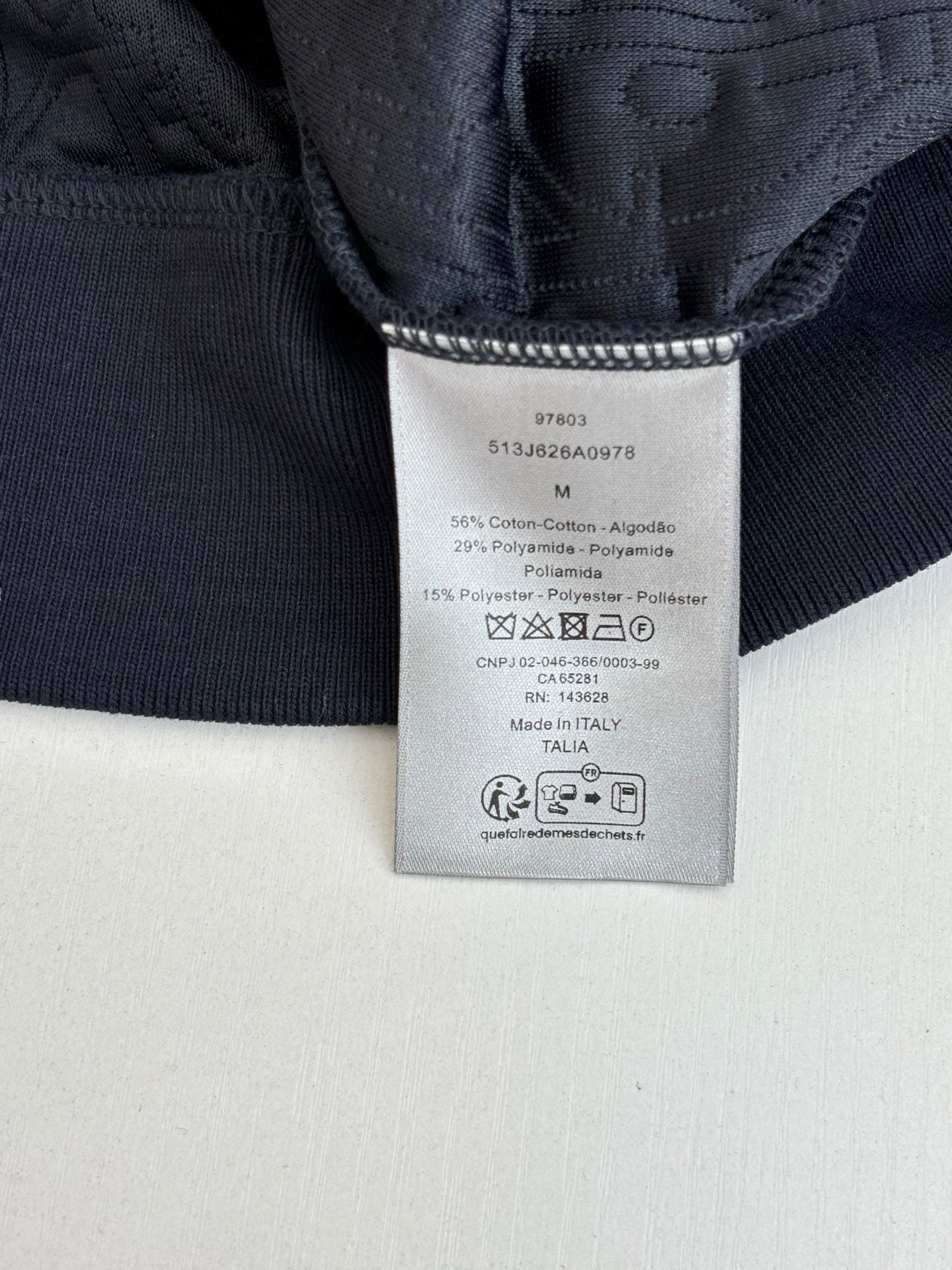 Dark long garment with woven care label