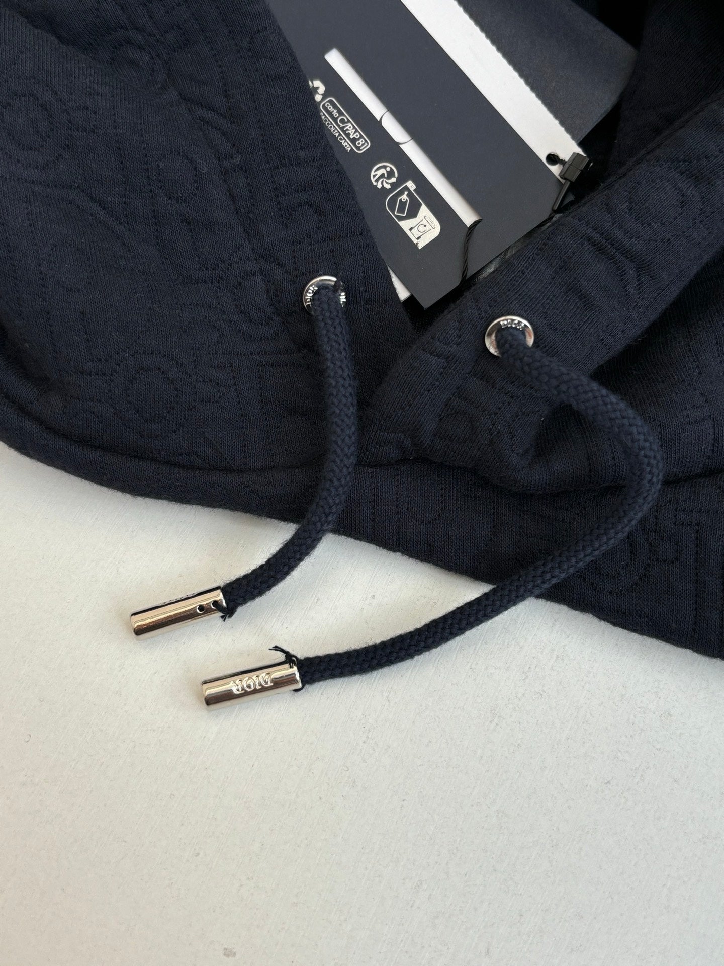 Dior navy hoodie close-up, round drawcord tips and interior label