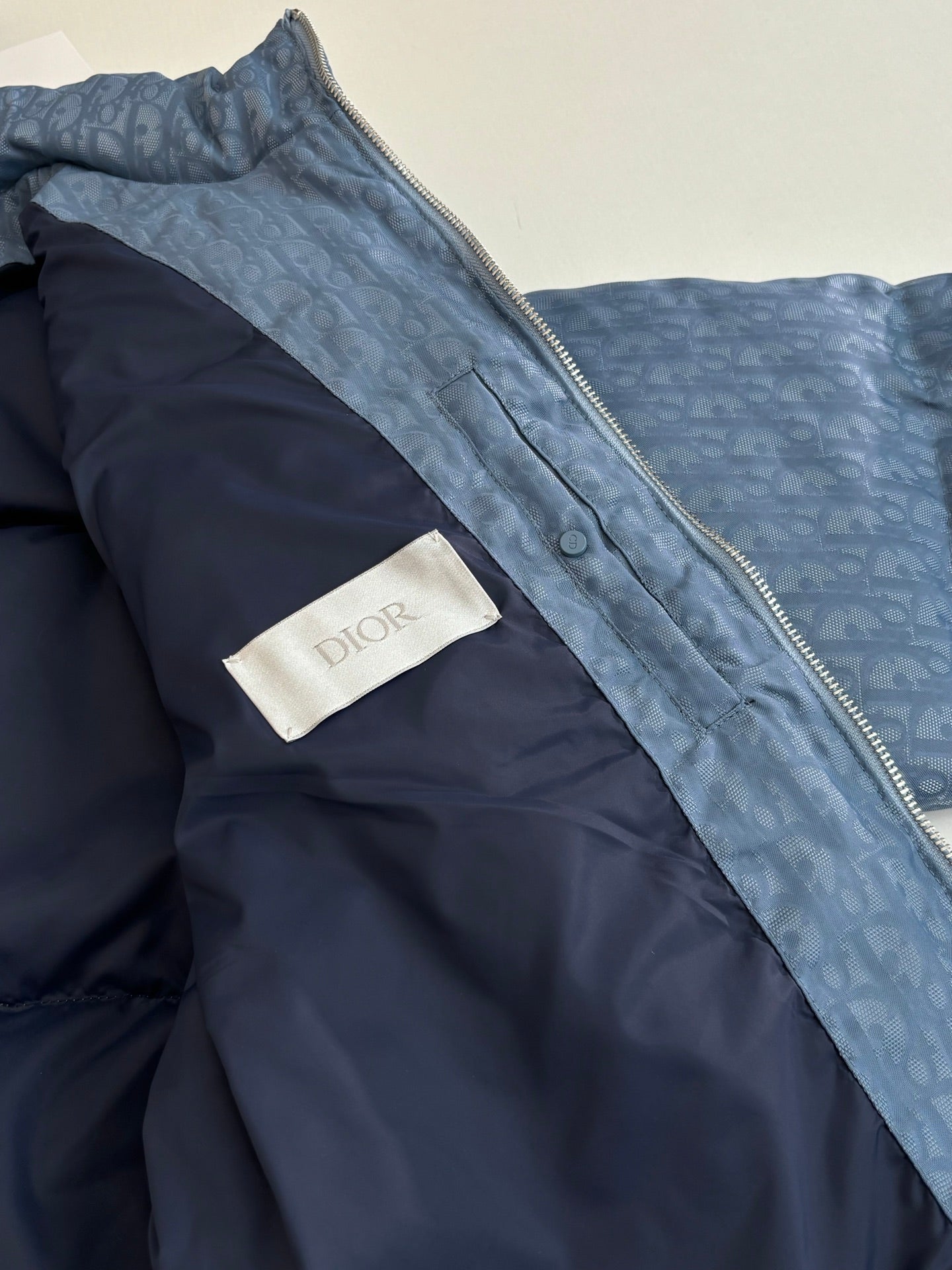 Blue Dior puffer jacket interior with dark lining and Dior logo label patch