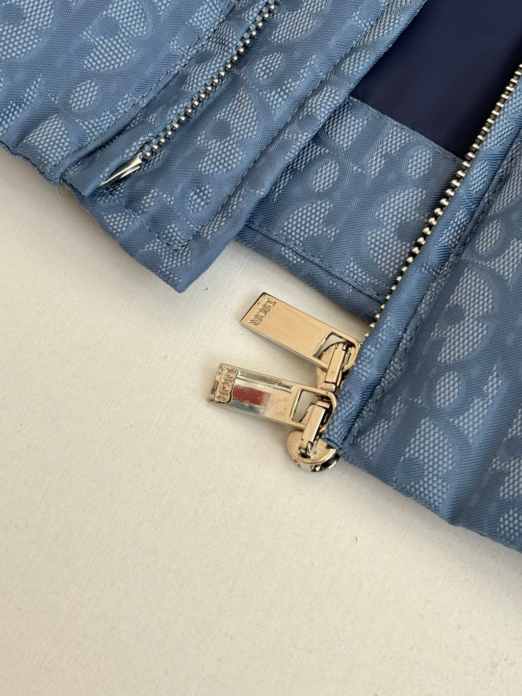 Blue Dior puffer jacket close-up of gold zippers and logo hardware