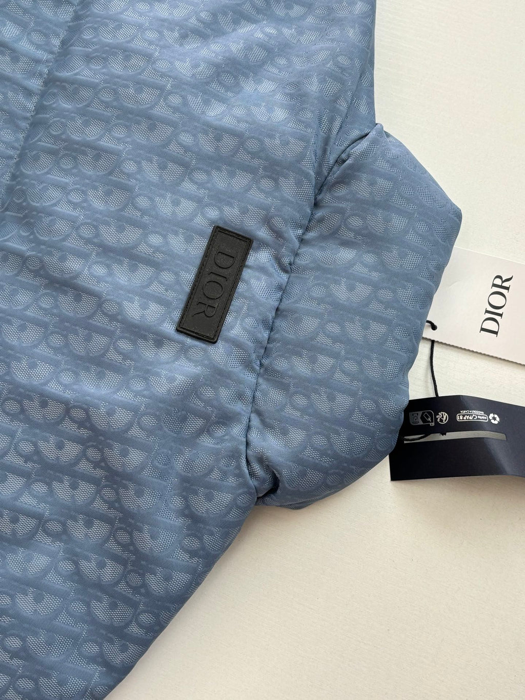 Blue Dior puffer jacket side detail with logo patch near the collar