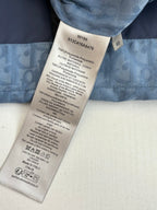 Blue long-sleeve shirt with care label showing size, material, and washing instructions