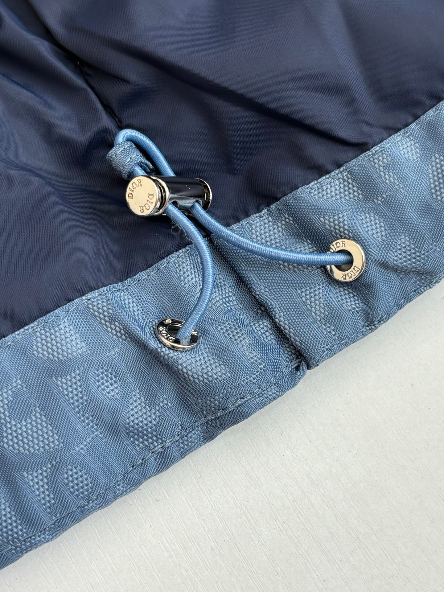 Blue Dior puffer jacket close-up of cord toggles and zipper hardware