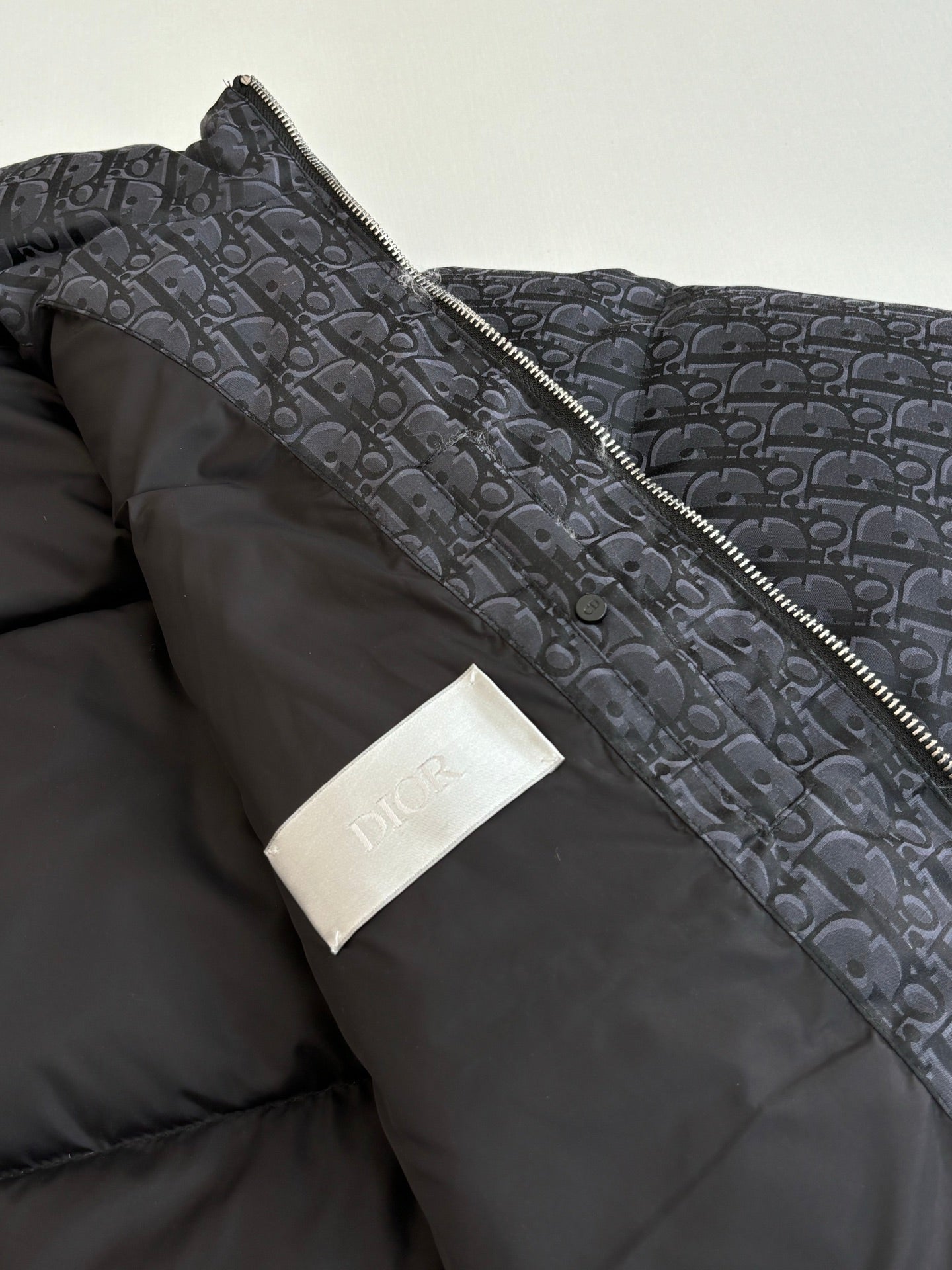Dior quilted jacket shoulder and collar detail, with logo patch and dark lining.