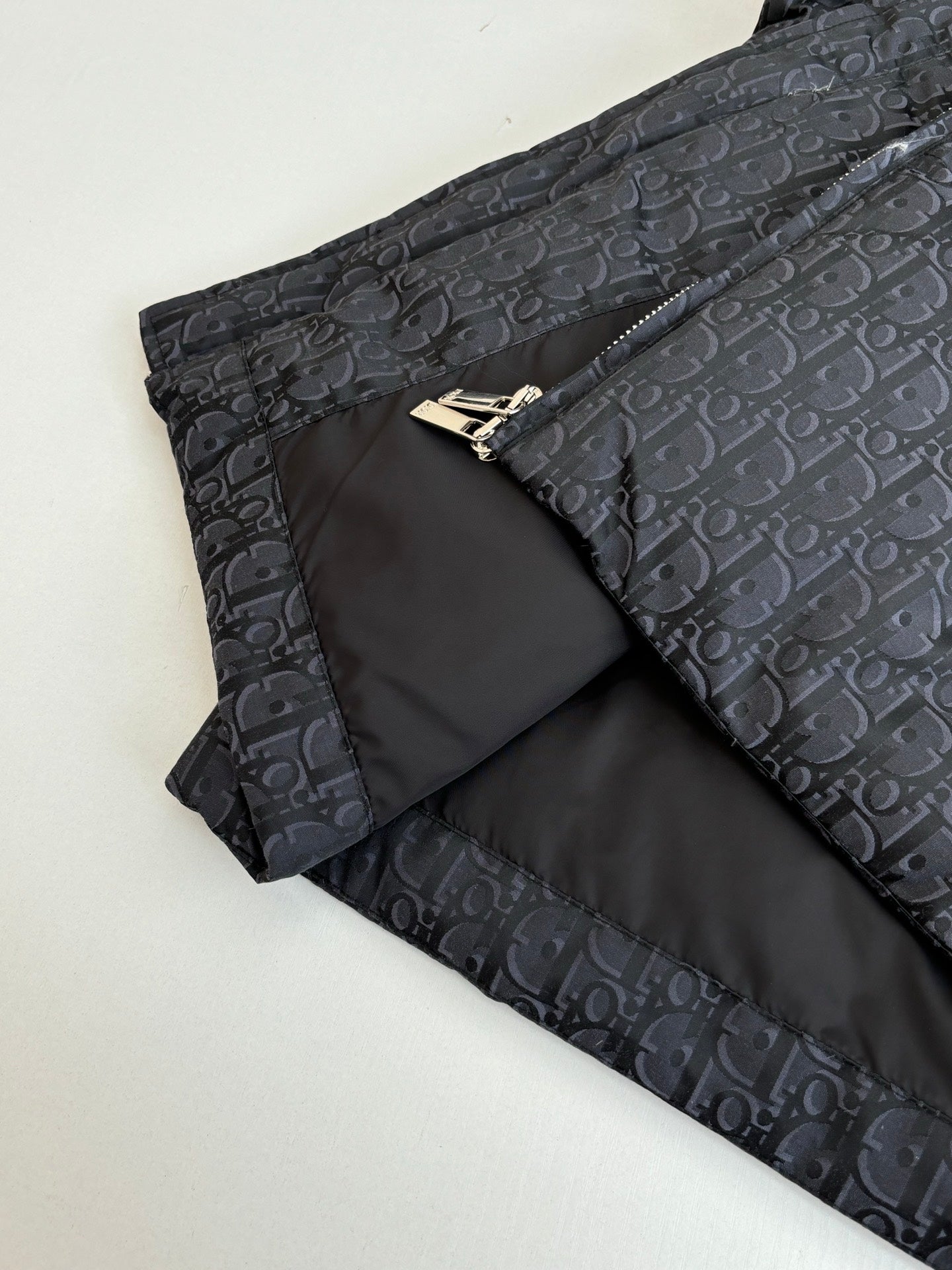Long quilted Dior jacket with zipper and dark monogram shell, folded with inner lining.