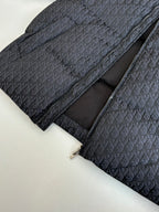 Long quilted Dior jacket with zip front, dark monogram outer and black inner lining.
