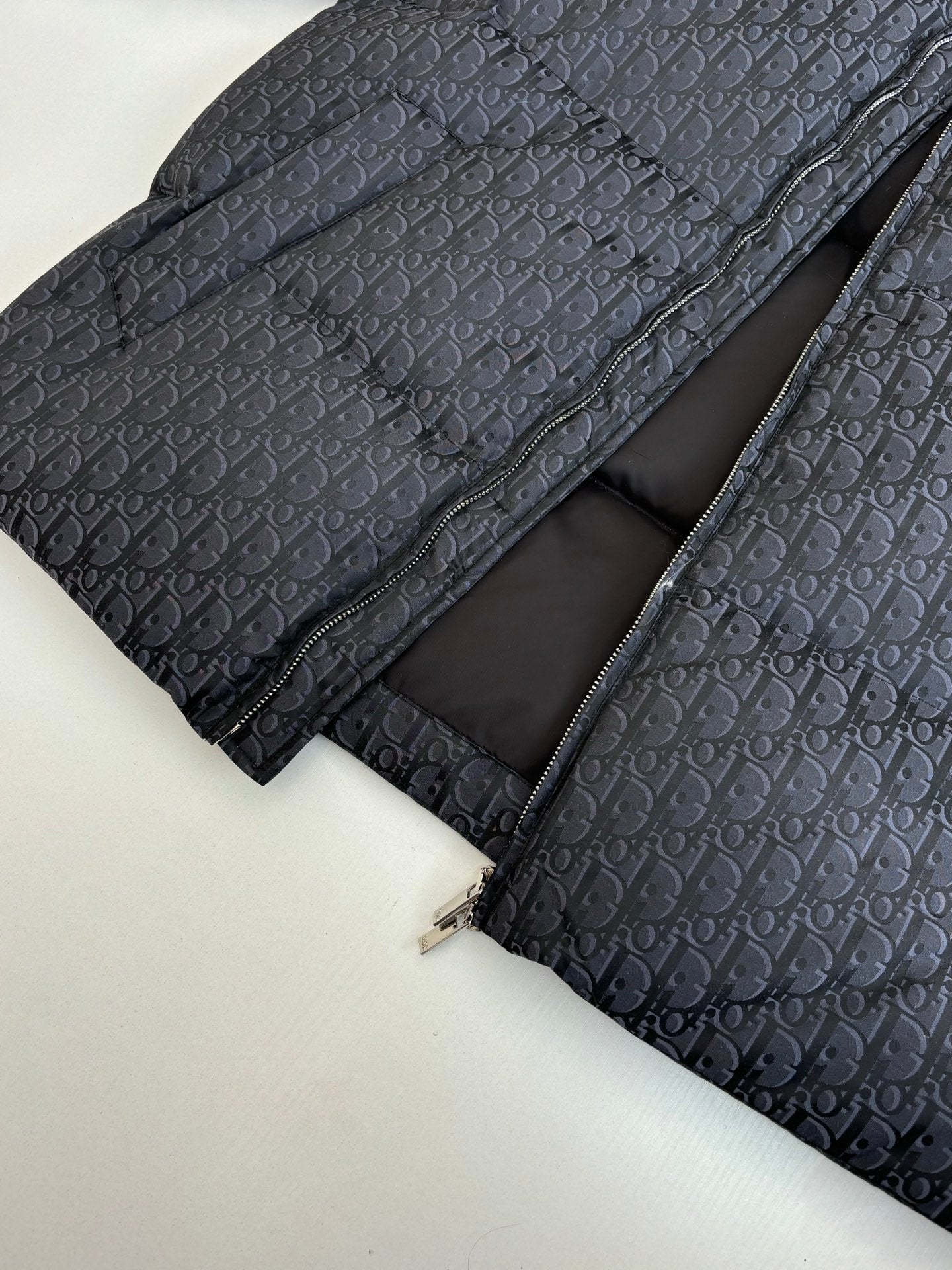 Long quilted Dior jacket with zip front, dark monogram outer and black inner lining.