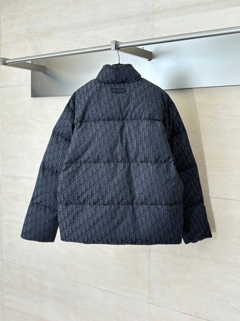 Long quilted Dior jacket, back view, standing collar, dark textured monogram fabric.