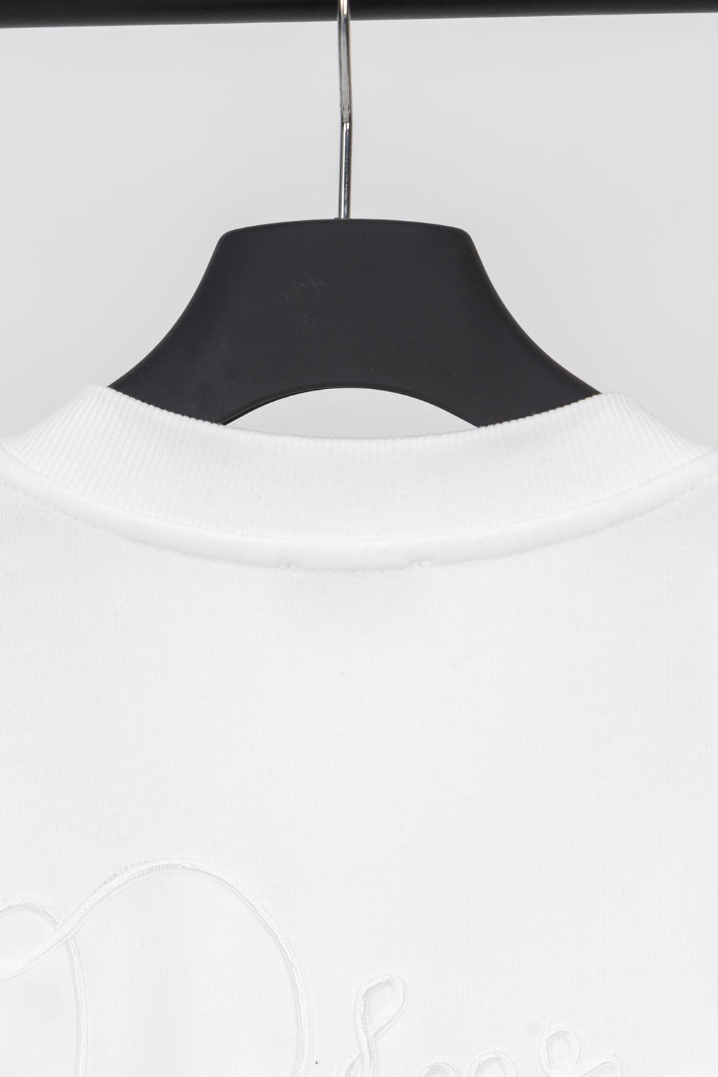 White sweatshirt neckline with ribbed collar, hanging on a dark hanger