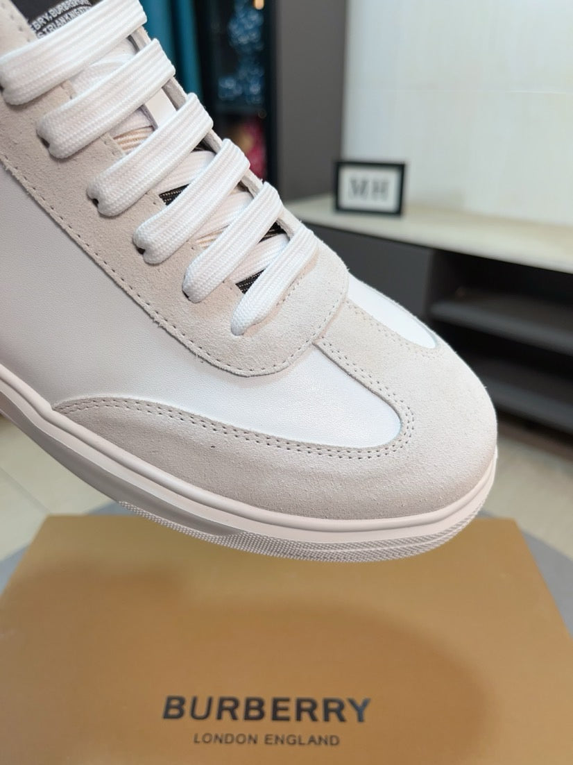 Close-up of a white sneaker with beige leather side and stitched toe