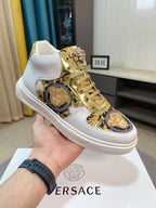White mid-top sneaker with gold lace eyelets and blue-gold Medusa emblem patch