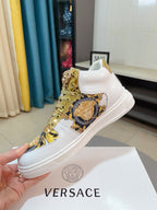 White mid-top sneaker with gold lace details and blue-gold Medusa emblem on side