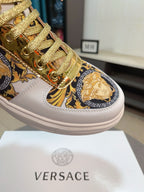 Close-up of white sneaker toe with gold lace hardware and blue-gold Medusa emblem