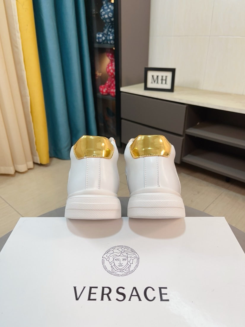 Back view of white mid-top sneakers with metallic gold heel caps and flat sole