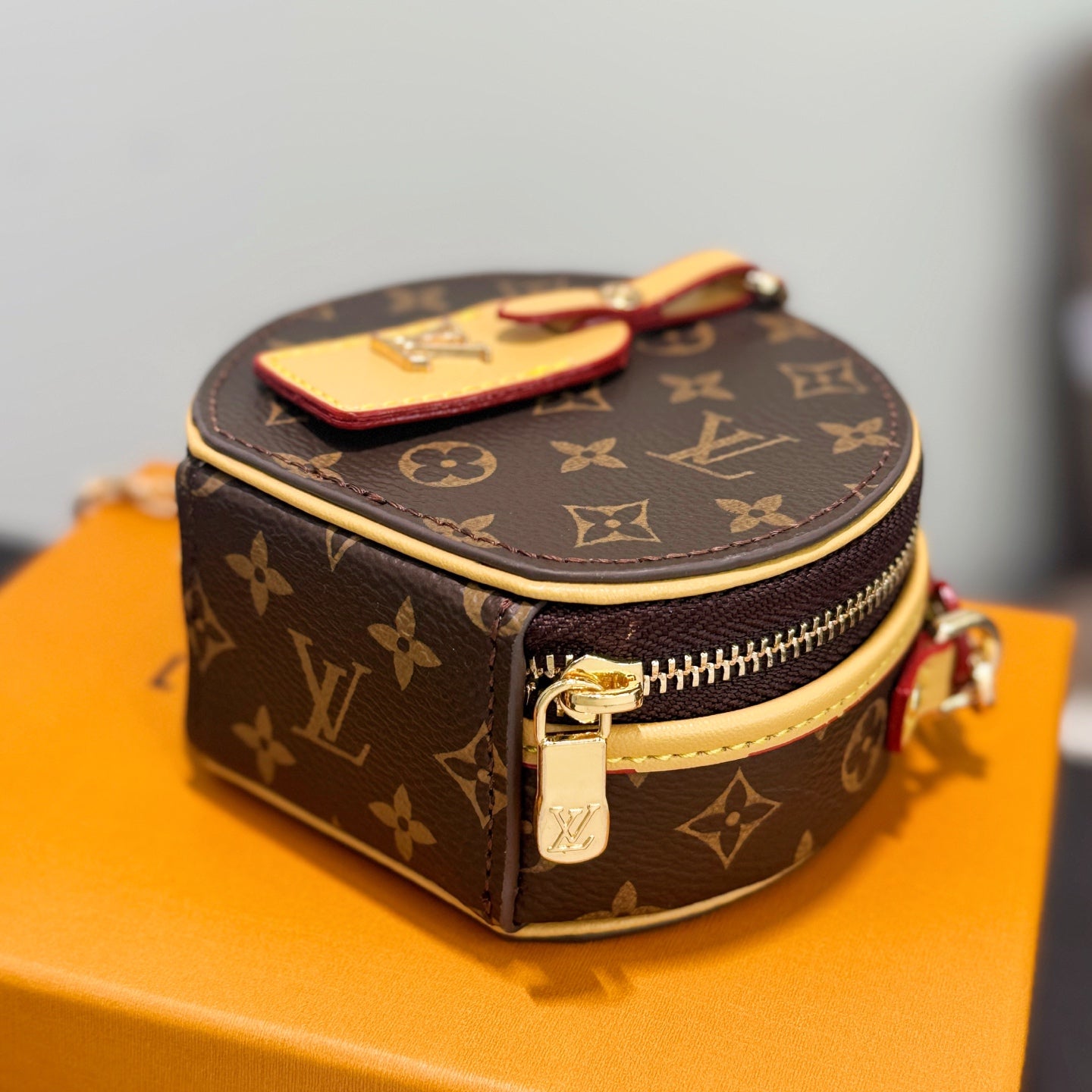 Small round bag with brown monogram canvas, top handle, gold zipper and front pocket