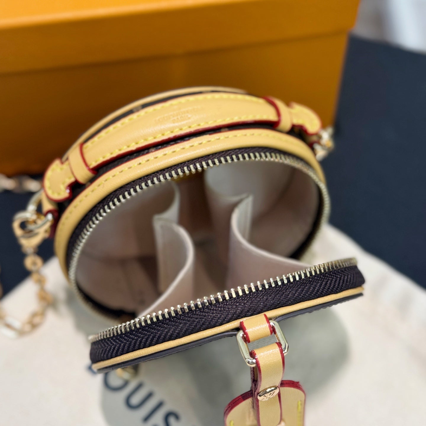 Round mini bag open with white fabric lining and gold zipper track visible at top
