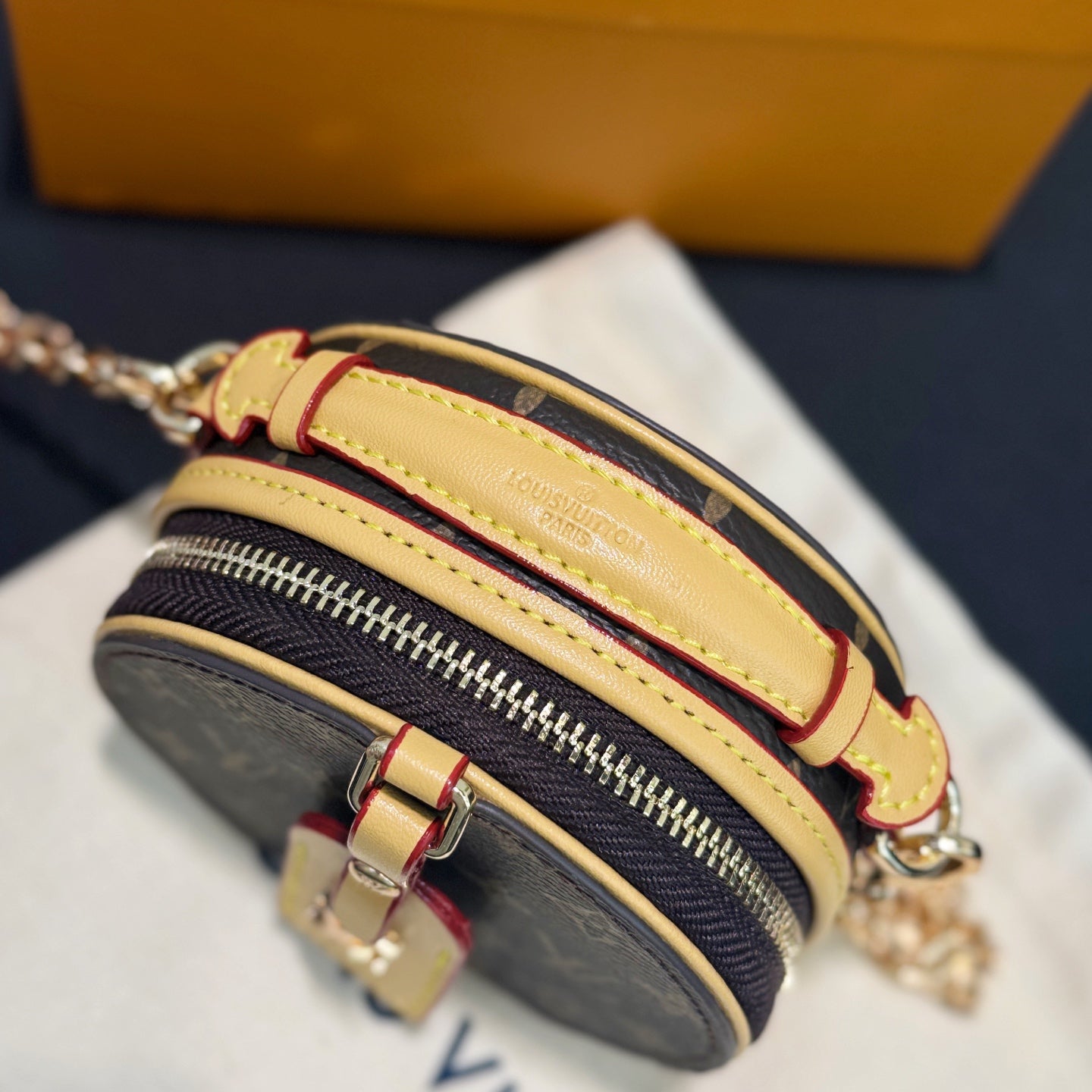 Monogram mini bag side view with layered trim and gold-tone zipper detail