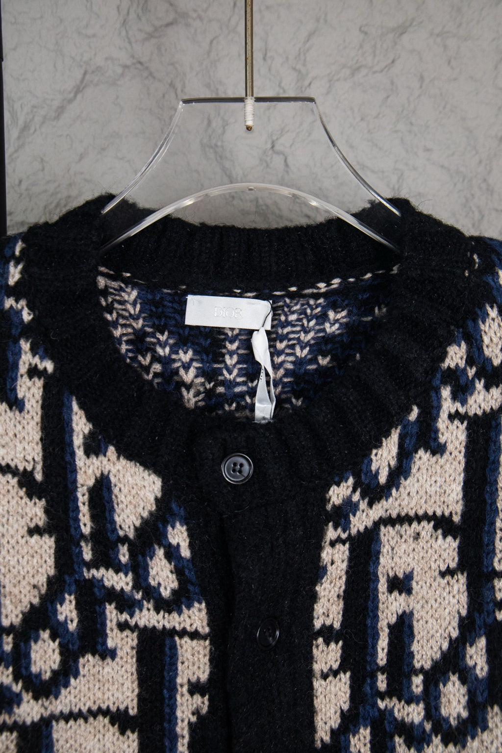 Dior knit cardigan neckline with logo pattern, black placket and visible button.