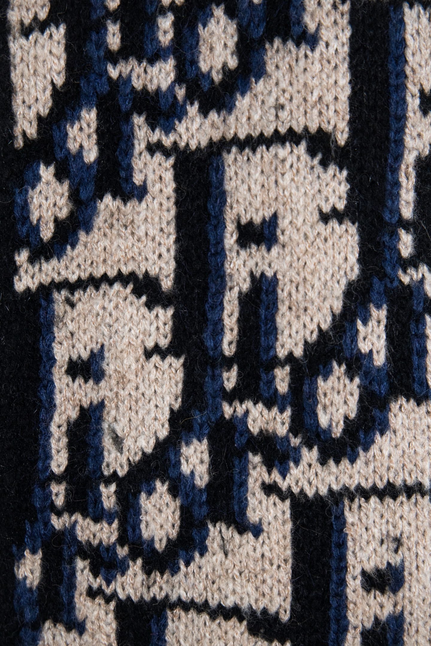 Navy and cream knit pattern sweater detail with repeating logo-style letters.