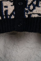 Dior knit cardigan close-up of black button placket and navy/cream logo pattern.