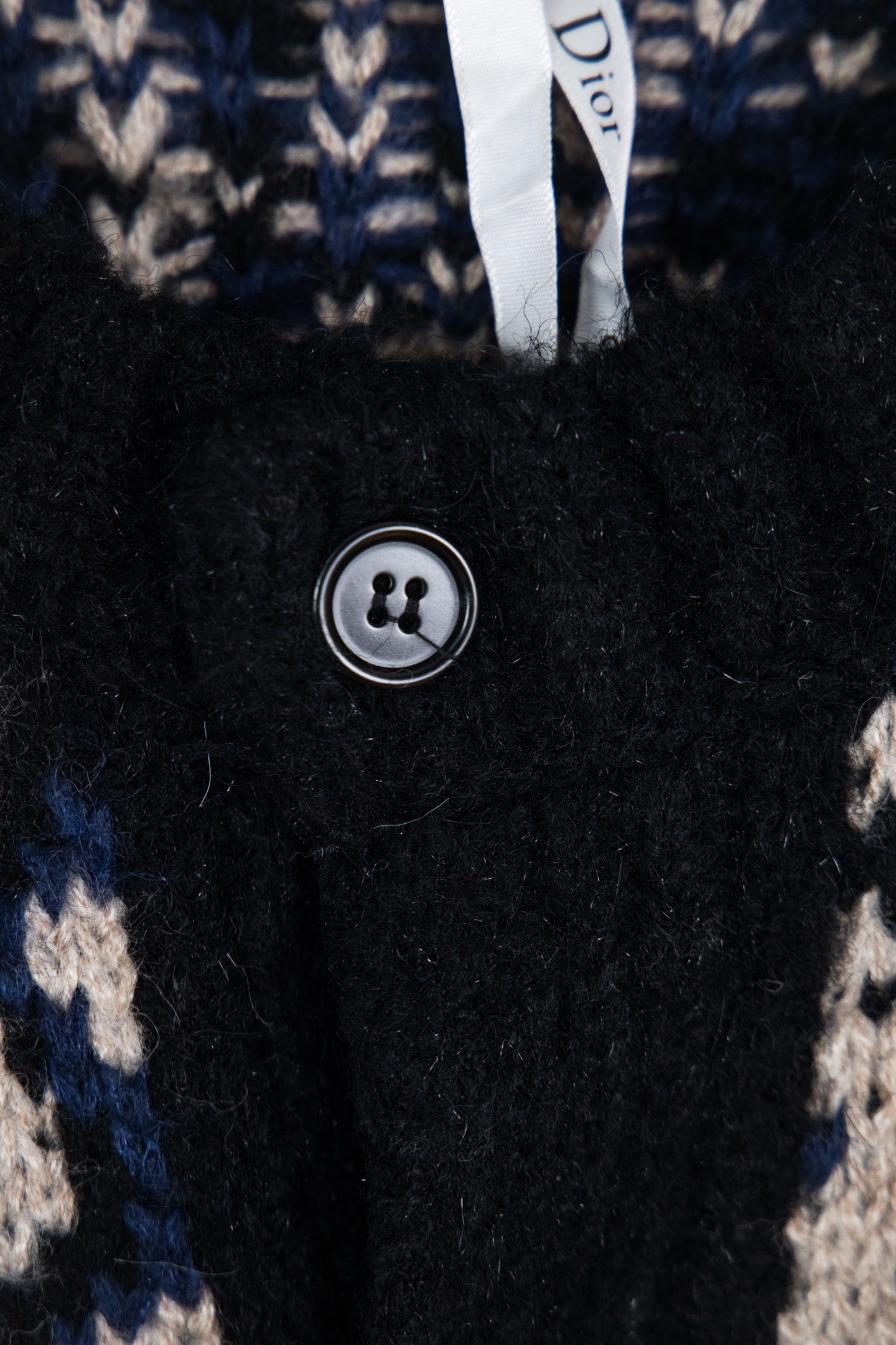 Dior knit cardigan close-up: black button and navy/cream logo knit pattern.