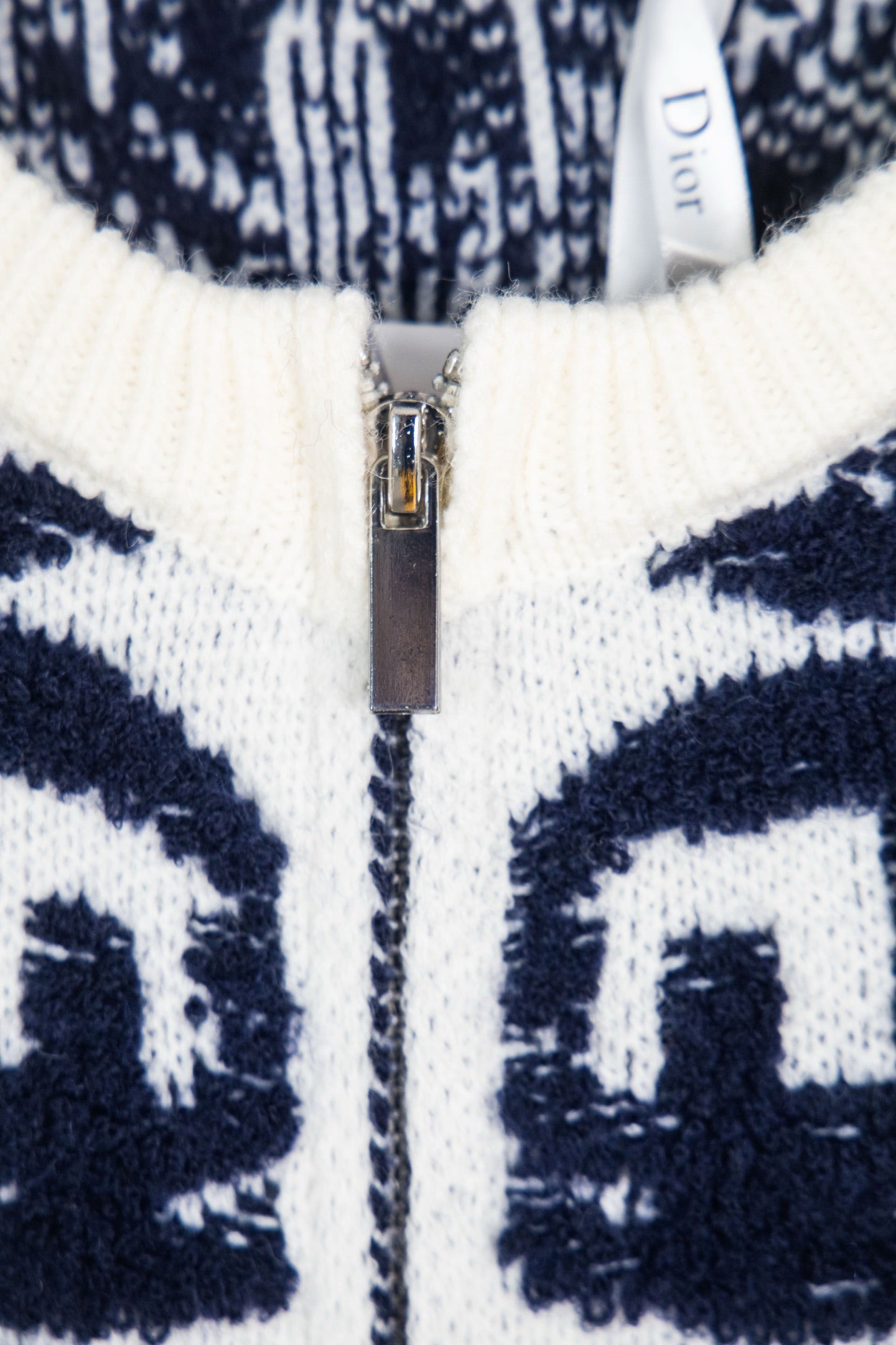 Navy-and-white patterned knit sweater with metal zip front and ribbed collar.