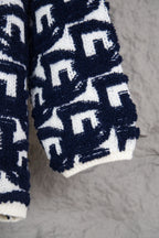 Lower sleeve and hem of navy-and-white patterned knit sweater with Dior motifs.