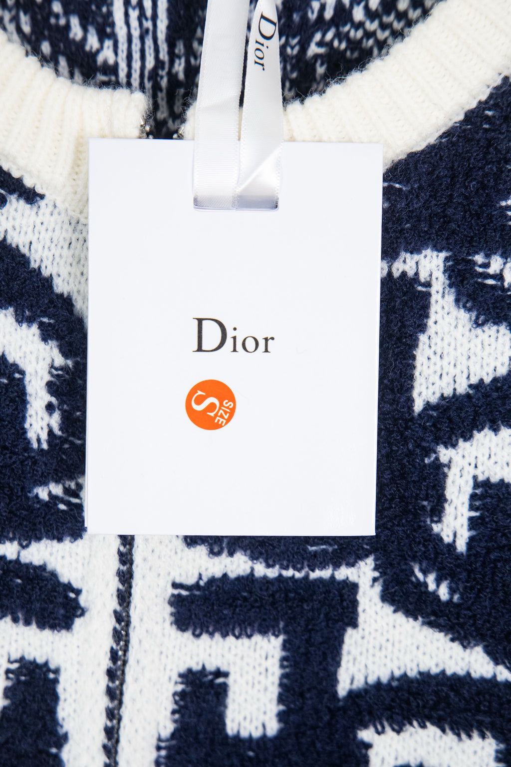 Navy-and-white Dior monogram knit sweater with hanging retail tag.