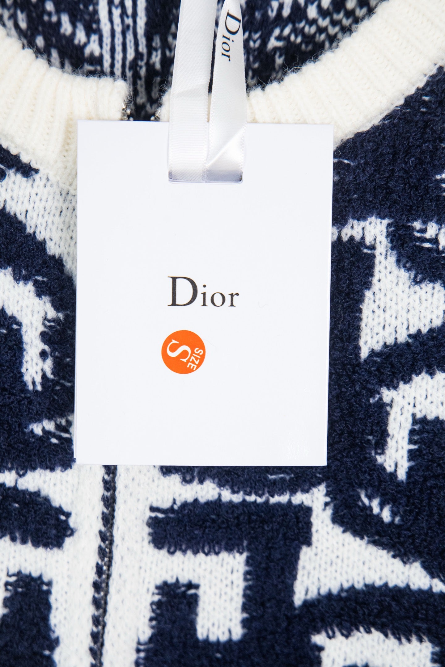 Navy-and-white Dior monogram knit sweater with hanging retail tag.