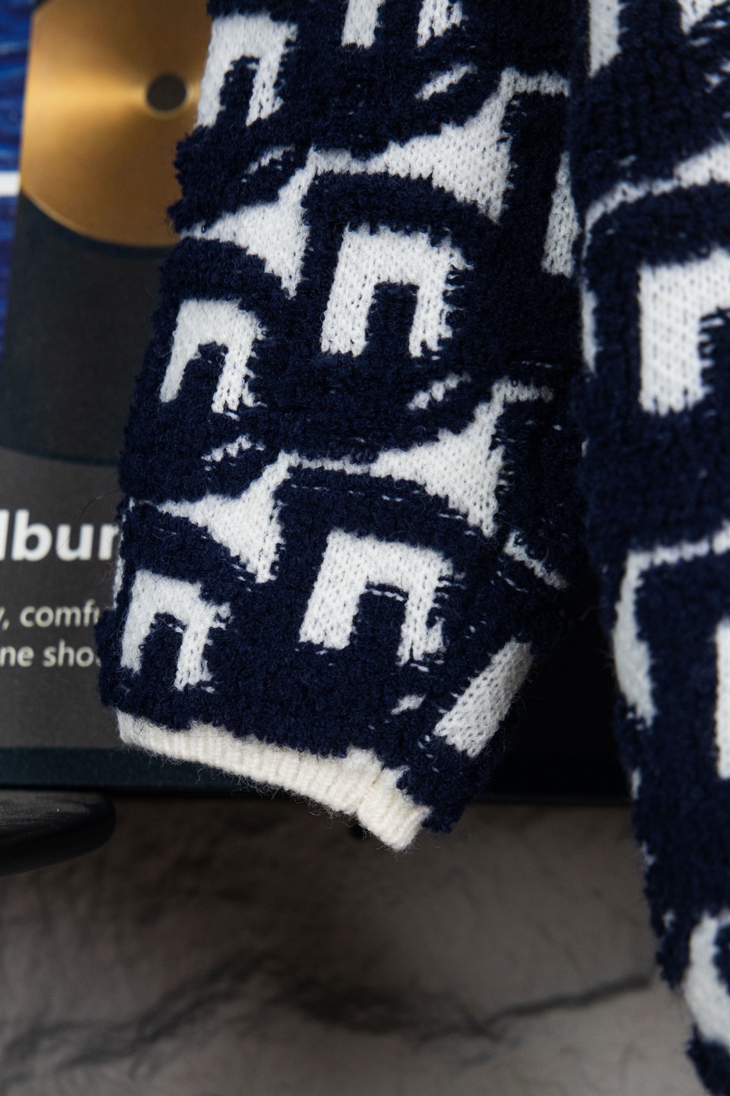 Sleeve of navy-and-white patterned knit sweater with repeating Dior motifs.