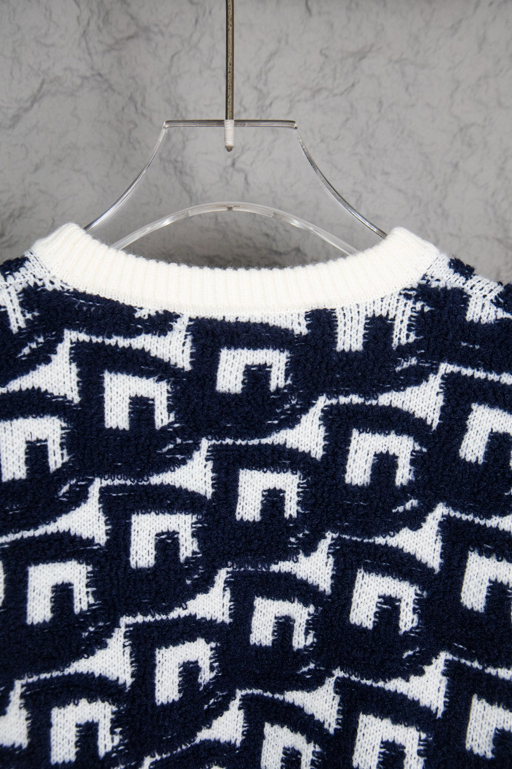 Back of navy-and-white knit sweater with repeating Dior motifs pattern.