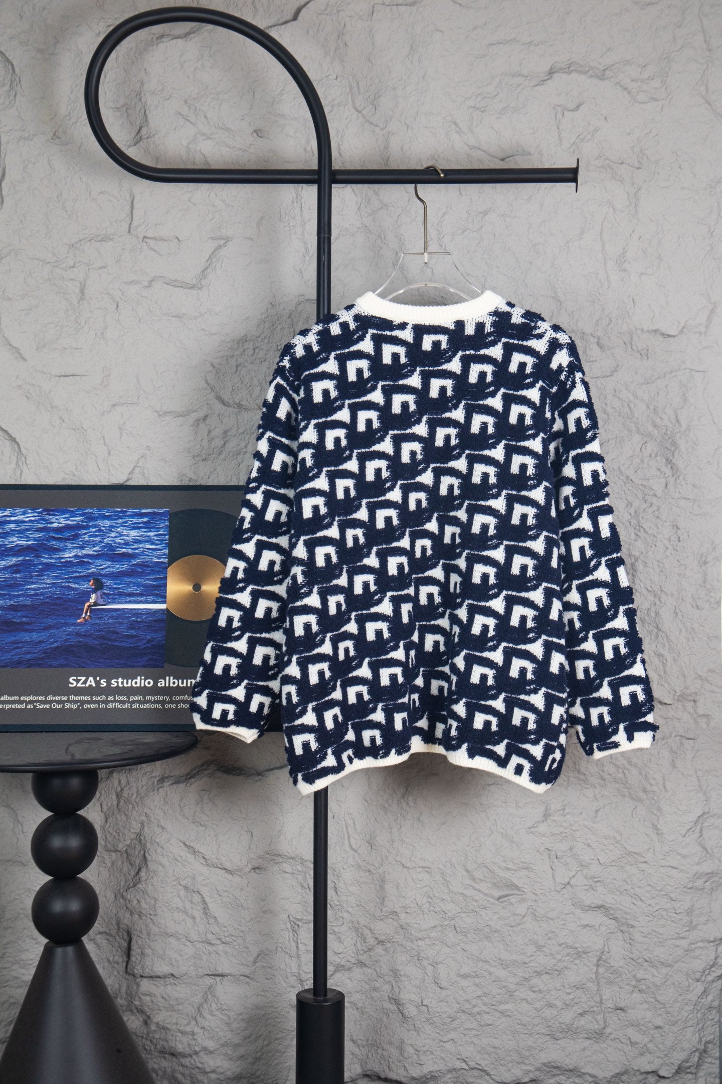 Long knit sweater back on hanger, navy-and-white Dior logo pattern.