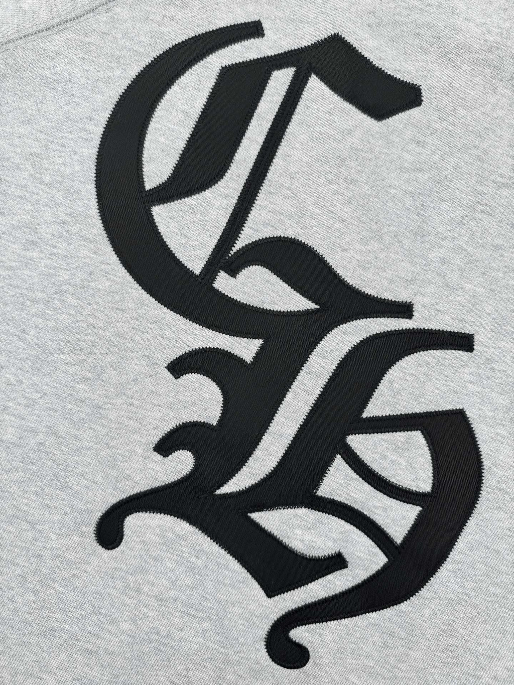 Black stylized emblem graphic on heather gray sweatshirt front