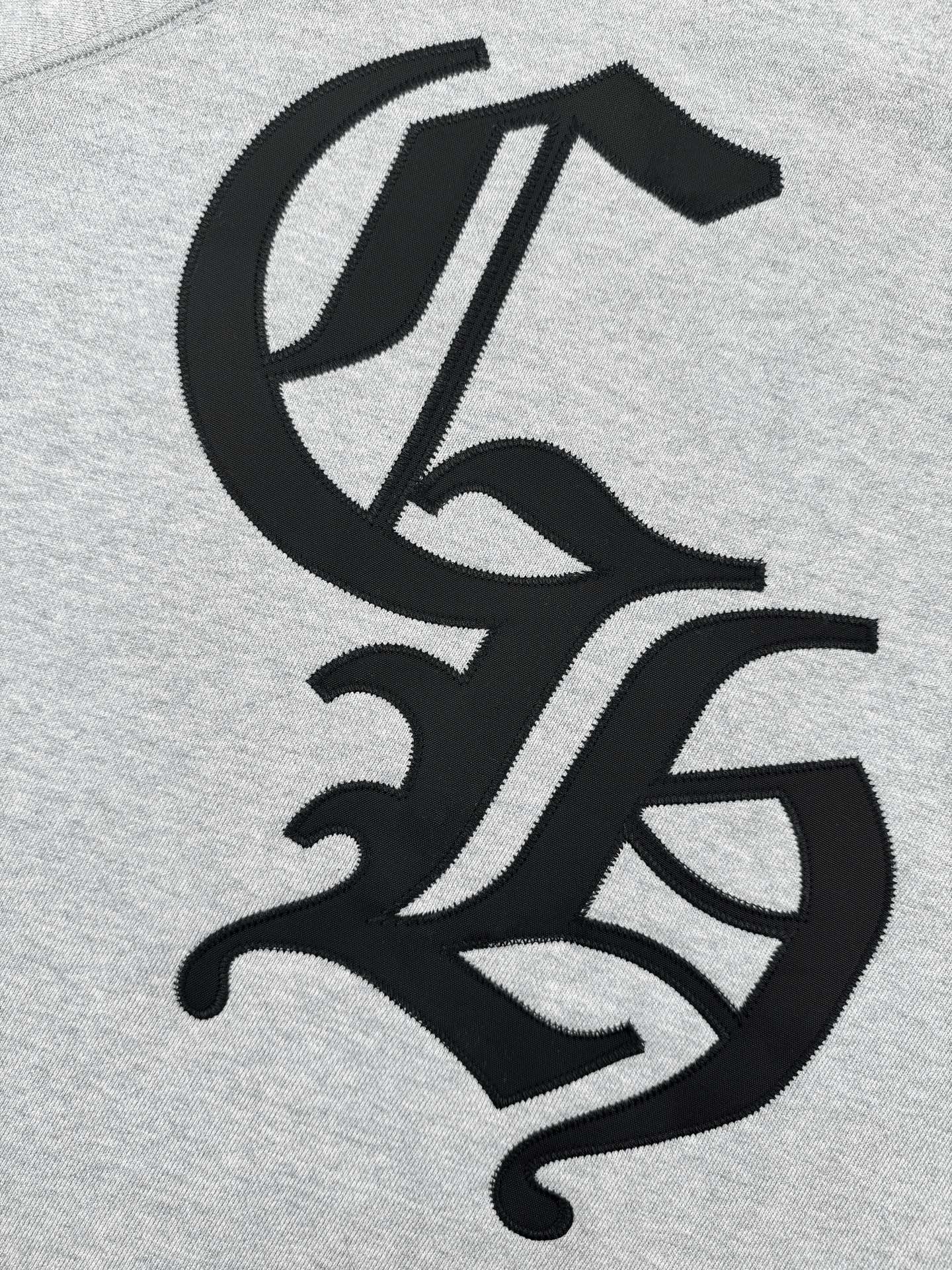 Black stylized emblem graphic on heather gray sweatshirt front