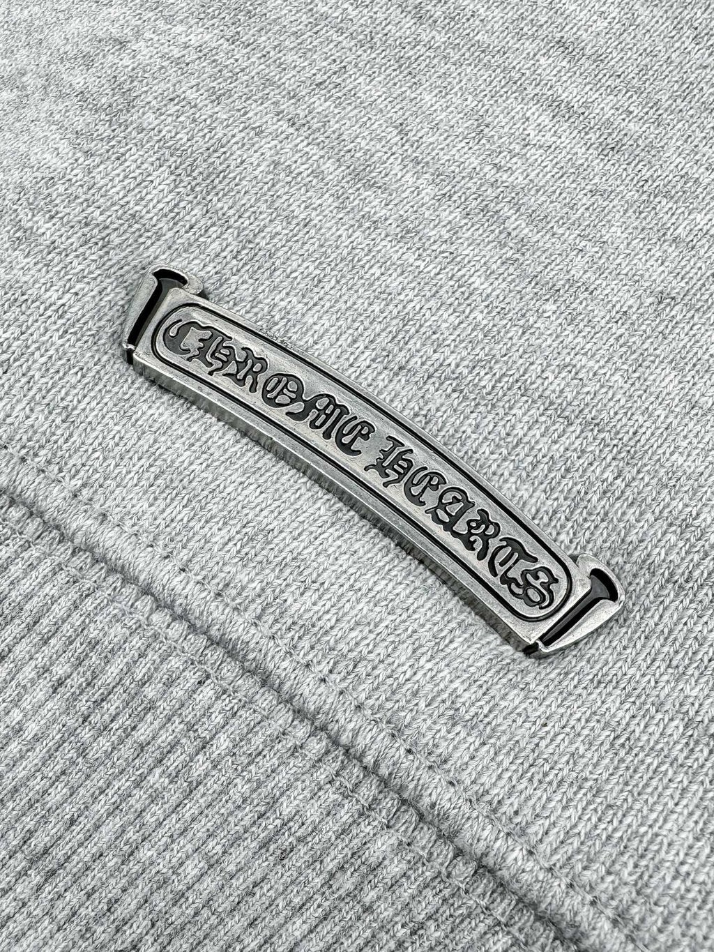 Metallic brand tag on heather gray sweatshirt seam
