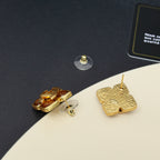 Gold-tone Chanel logo stud earrings with amber enamel, shown from side angle