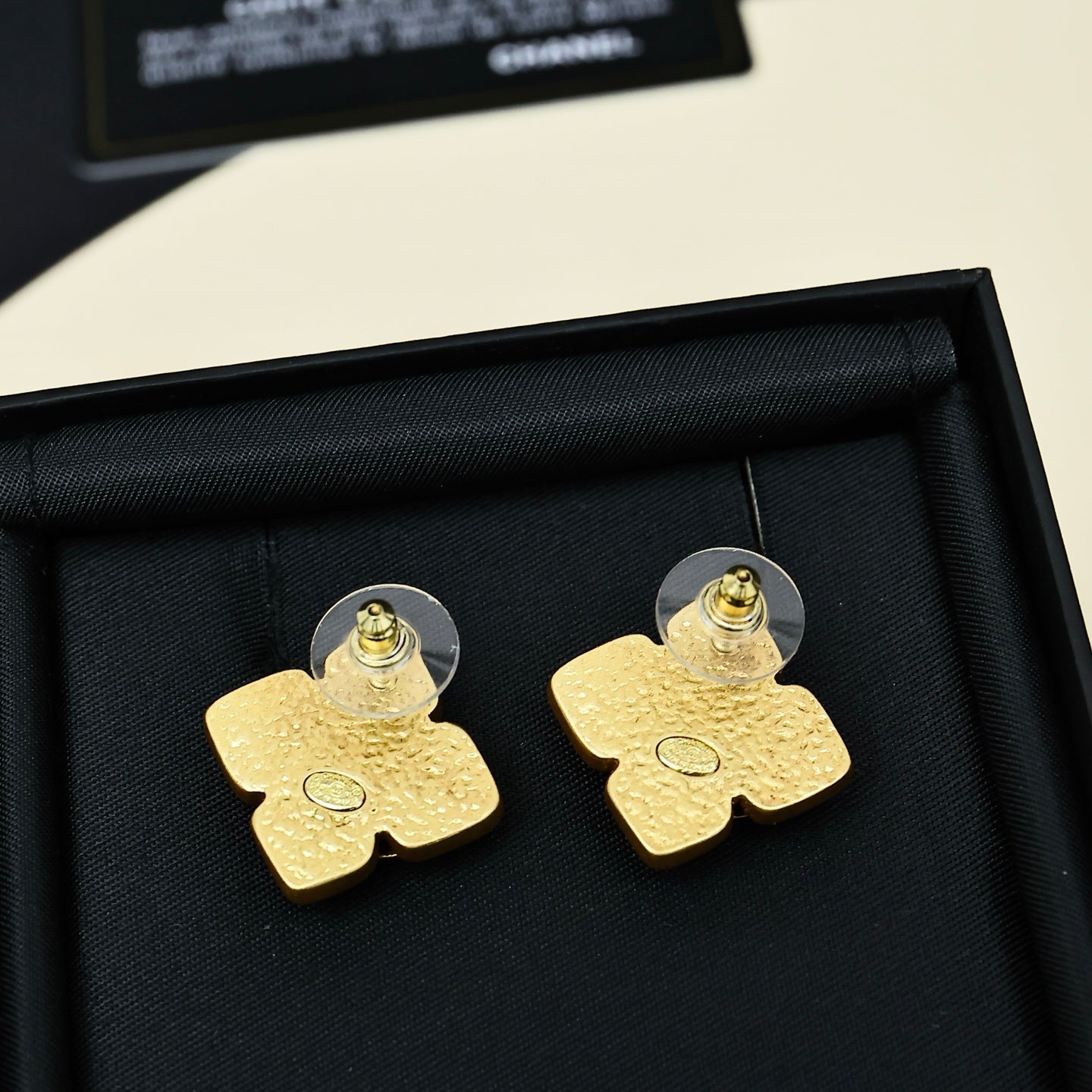 Gold-tone Chanel logo stud earrings with black backing, round post and textured face