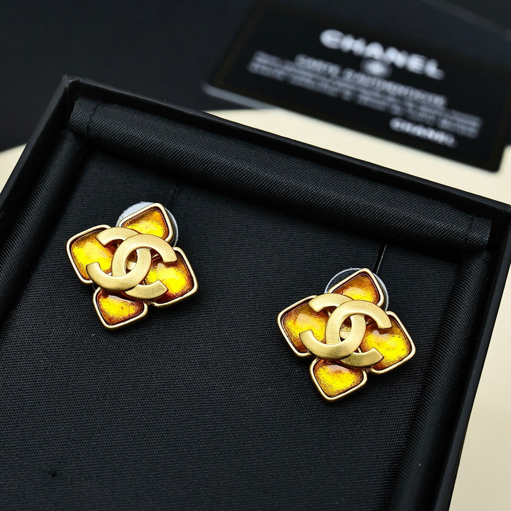 Gold-tone Chanel logo stud earrings with amber enamel center and dark border, pair